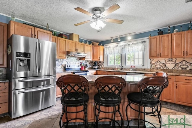 219 N College St, Pembroke, GA 31321 - kitchen with a kitchen island, a ceiling fan, a sink, under cabinet range hood, and stainless steel appliances