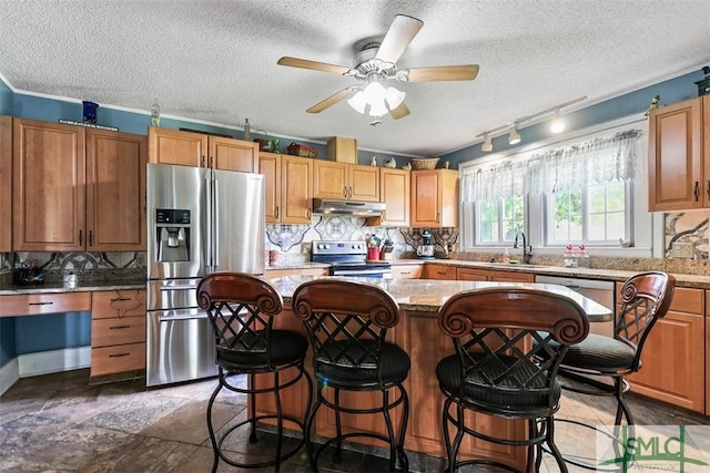 219 N College St, Pembroke, GA 31321 - kitchen featuring under cabinet range hood, a textured ceiling, appliances with stainless steel finishes, and tasteful backsplash