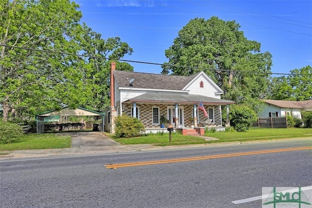 219 N College St, Pembroke, GA 31321 - view of front of house featuring a porch, driveway, a front yard, a carport, and stone siding