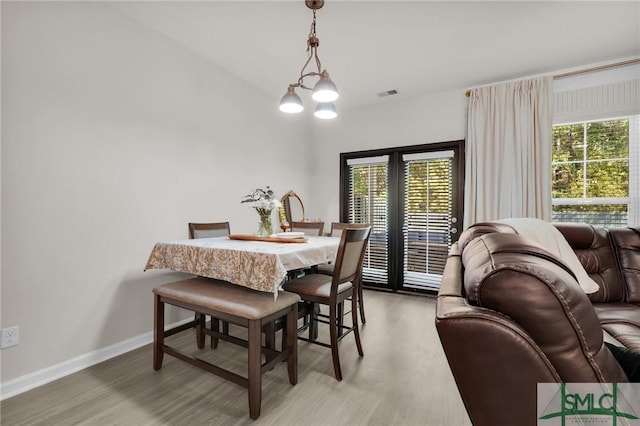 dining room featuring light wood-style floors, baseboards, plenty of natural light, and visible vents