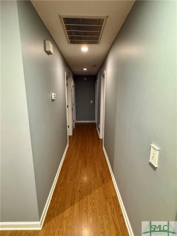 corridor with visible vents, baseboards, and wood finished floors