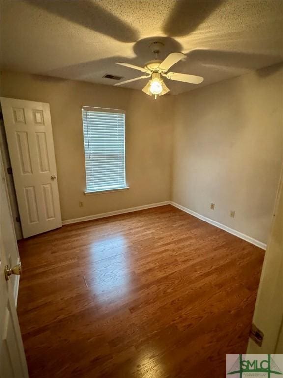 unfurnished room featuring visible vents, baseboards, a textured ceiling, and wood finished floors