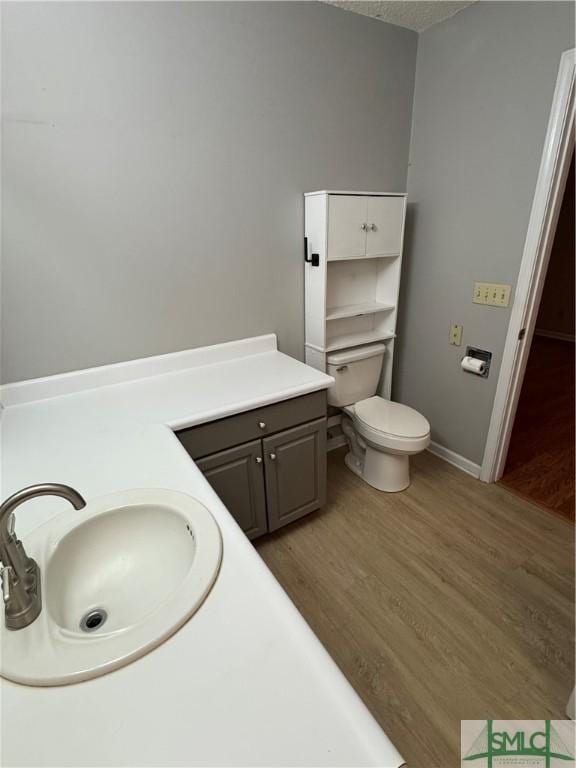bathroom featuring toilet, baseboards, a sink, and wood finished floors
