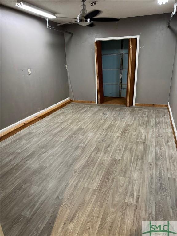 interior space featuring baseboards, a ceiling fan, and wood finished floors