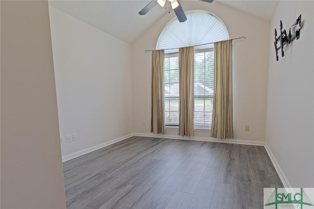 unfurnished room with baseboards, a ceiling fan, wood finished floors, and vaulted ceiling