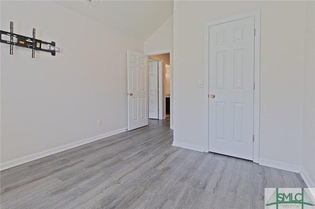 unfurnished bedroom with baseboards, wood finished floors, and lofted ceiling