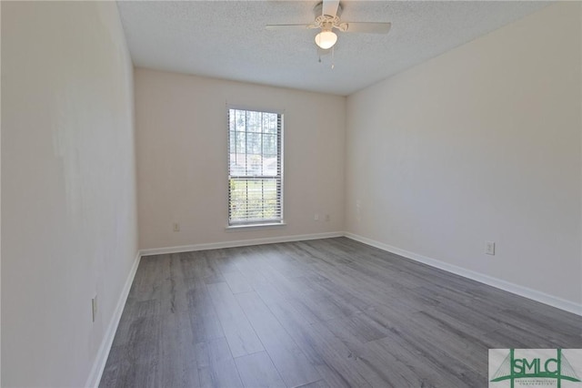 spare room featuring baseboards, a textured ceiling, dark wood finished floors, and a ceiling fan