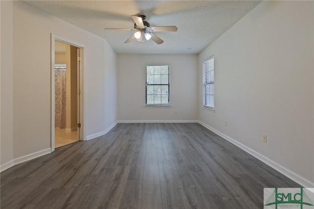 empty room with a textured ceiling, ceiling fan, dark wood finished floors, and baseboards