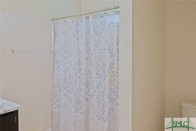bathroom featuring toilet, curtained shower, and vanity