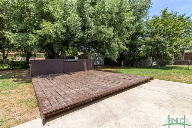 view of patio with fence, an outbuilding, a shed, and a wooden deck