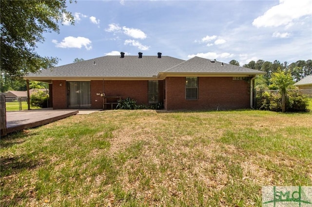 back of house featuring brick siding, fence, a yard, and a wooden deck