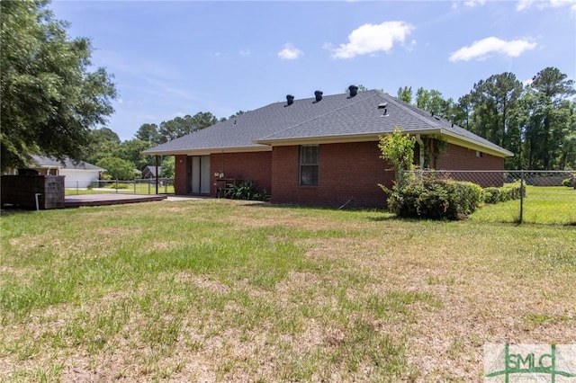view of side of property featuring fence, a lawn, and brick siding