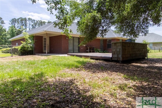 back of property with fence, a lawn, and a deck