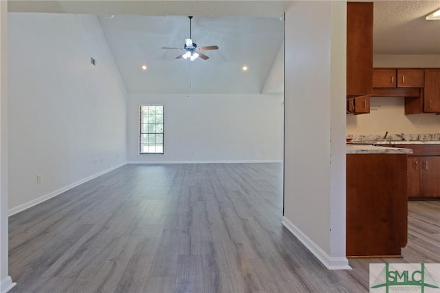 unfurnished living room featuring baseboards, a ceiling fan, wood finished floors, and lofted ceiling