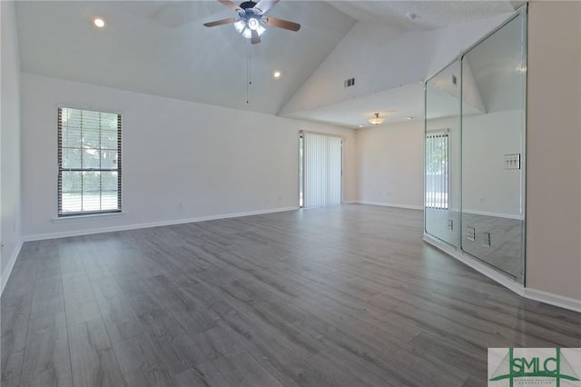 unfurnished room featuring baseboards, ceiling fan, a wealth of natural light, and wood finished floors