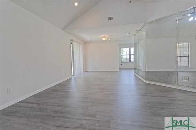 unfurnished room with visible vents, wood finished floors, high vaulted ceiling, baseboards, and recessed lighting