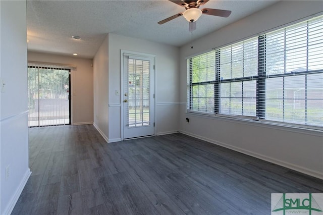 interior space with baseboards, a ceiling fan, dark wood finished floors, and a textured ceiling