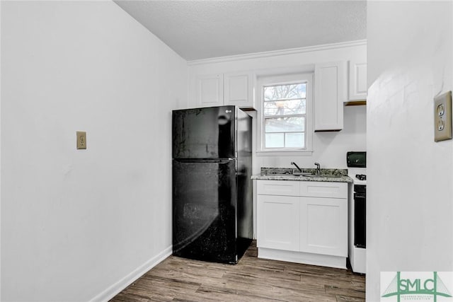 819 W 51st St, Savannah, GA 31405 - kitchen featuring freestanding refrigerator, white cabinets, wood finished floors, light stone counters, and a sink