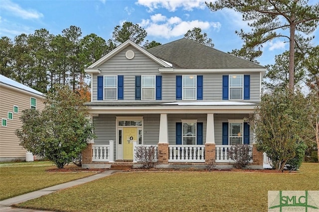 view of front of home with a porch, a shingled roof, brick siding, and a front yard