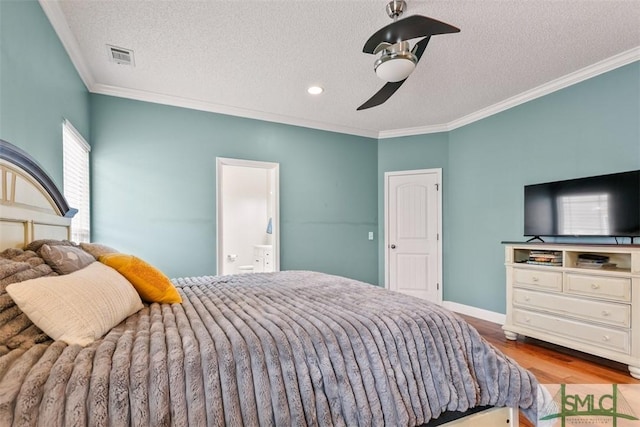 bedroom featuring crown molding, visible vents, wood finished floors, a textured ceiling, and ensuite bath
