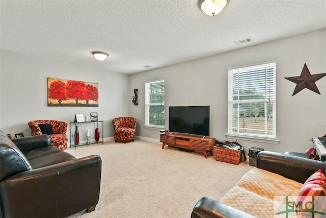 carpeted living area featuring a healthy amount of sunlight, a textured ceiling, and visible vents