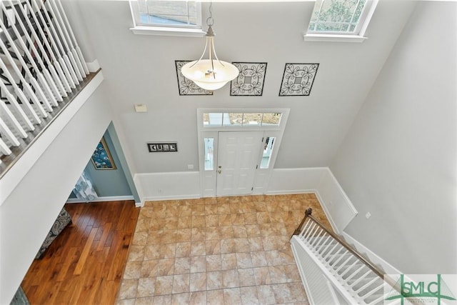 foyer featuring baseboards, a towering ceiling, wood finished floors, and a wealth of natural light