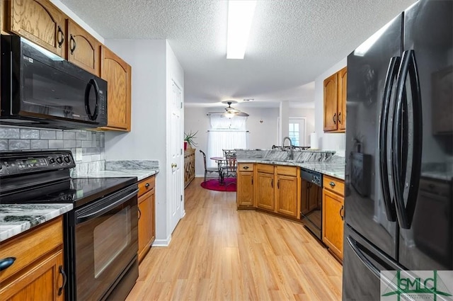 2504 Quacco Rd, Pooler, GA 31322 - kitchen with a peninsula, a textured ceiling, brown cabinets, light wood finished floors, and black appliances