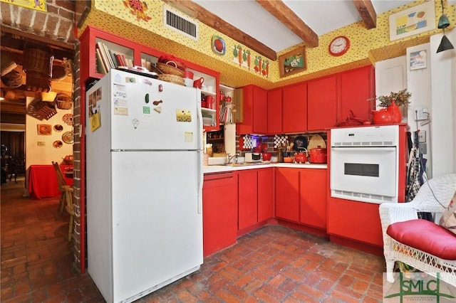 kitchen featuring white appliances, beam ceiling, visible vents, light countertops, and red cabinets
