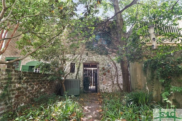 exterior space with central air condition unit, brick siding, and fence