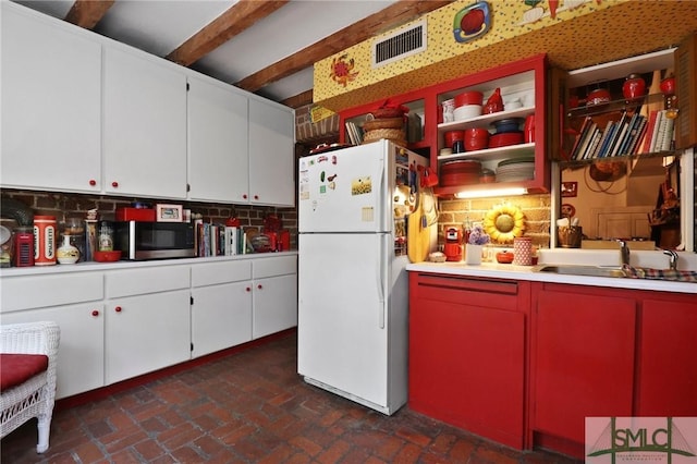 kitchen with freestanding refrigerator, brick floor, visible vents, stainless steel microwave, and a sink