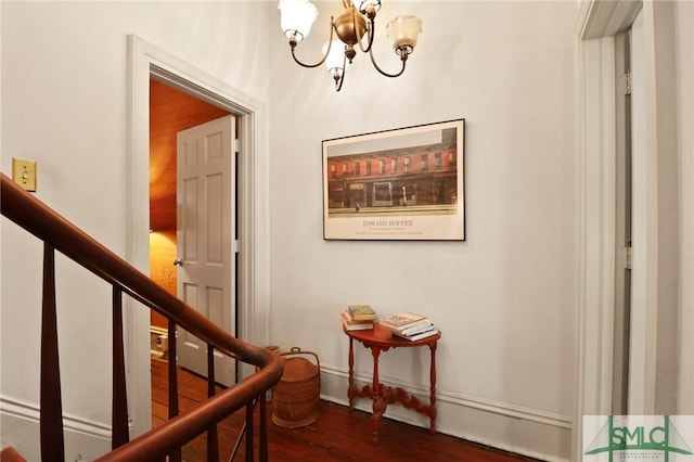hall featuring a chandelier, stairs, baseboards, and wood finished floors