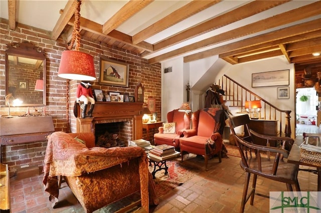 interior space with brick floor, visible vents, stairs, a brick fireplace, and beamed ceiling