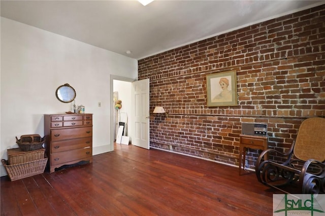 living area featuring brick wall and wood-type flooring