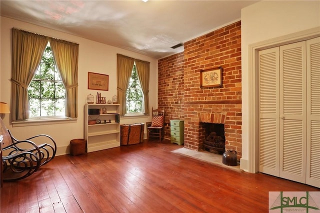 unfurnished room with baseboards, a brick fireplace, and hardwood / wood-style flooring