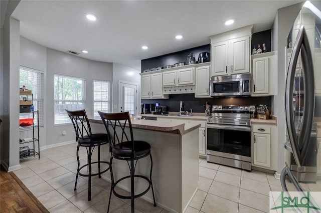 213 Rosehill Dr E, Rincon, GA 31326 - kitchen with a sink, stainless steel appliances, a breakfast bar area, visible vents, and a kitchen island