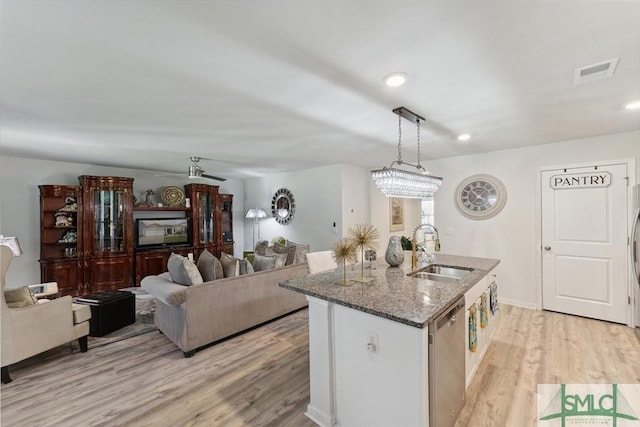 kitchen featuring a sink, dark stone countertops, visible vents, dishwasher, and light wood-style flooring