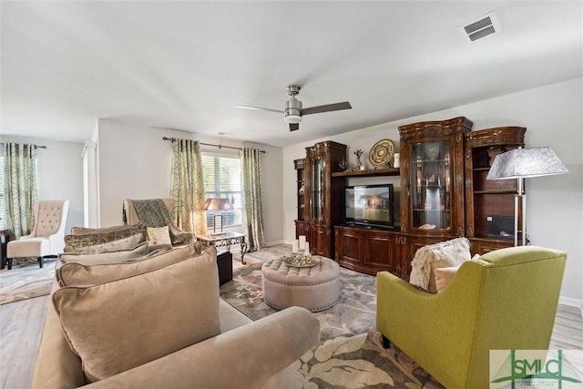 living area featuring baseboards, ceiling fan, visible vents, and wood finished floors