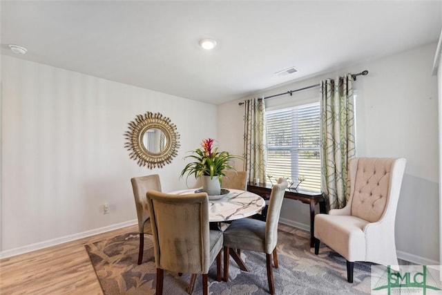 dining area with light wood finished floors, visible vents, and baseboards