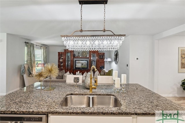 kitchen featuring a sink, dark stone counters, open floor plan, a kitchen island with sink, and dishwasher