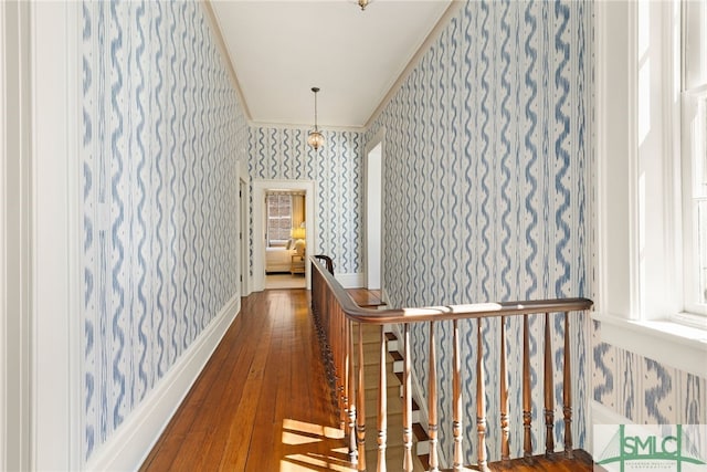 hallway featuring crown molding, an upstairs landing, wallpapered walls, and hardwood / wood-style flooring