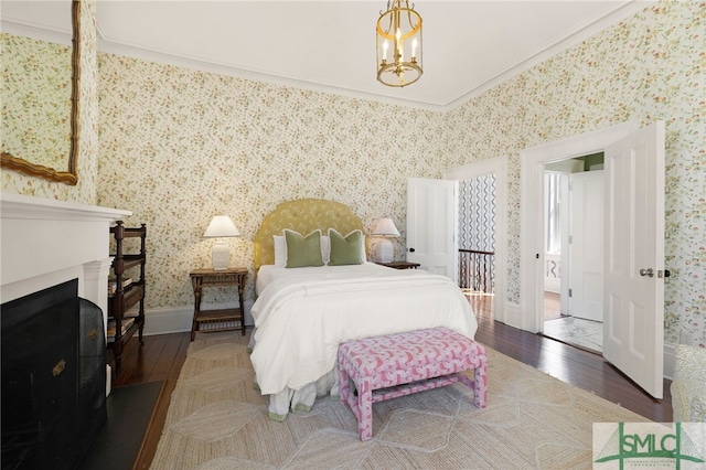bedroom featuring hardwood / wood-style floors, baseboards, crown molding, a notable chandelier, and wallpapered walls