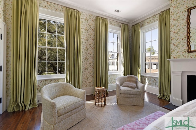 sitting room featuring visible vents, wood-type flooring, and wallpapered walls