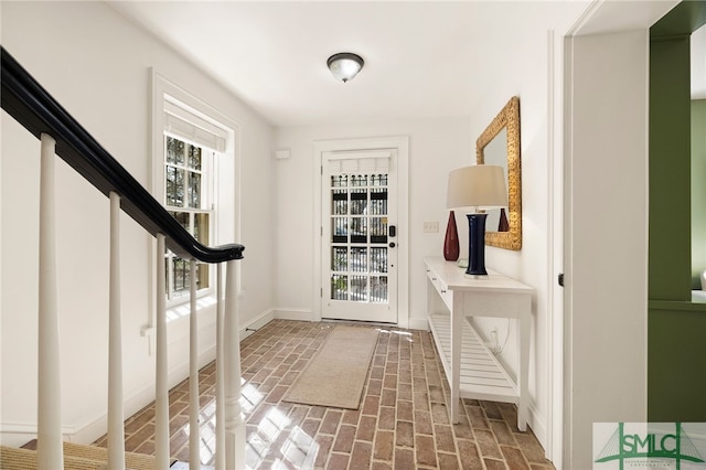 interior space featuring stairway, brick floor, and baseboards