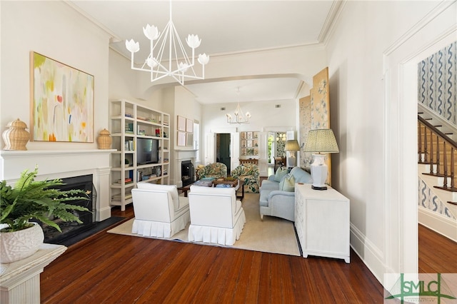 living area with wood finished floors, a fireplace, a notable chandelier, ornamental molding, and stairs