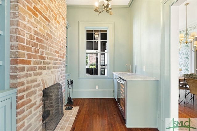 interior space featuring wine cooler, baseboards, dark wood finished floors, a chandelier, and indoor wet bar