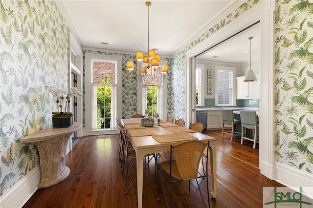 dining area featuring crown molding, dark wood-style flooring, wallpapered walls, and a chandelier
