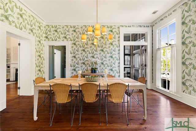 dining space with wallpapered walls, dark wood-type flooring, and an inviting chandelier