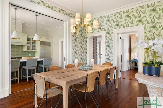dining area featuring crown molding, an inviting chandelier, wallpapered walls, and dark wood-type flooring
