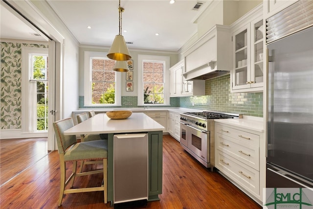 kitchen with premium appliances, crown molding, white cabinetry, light countertops, and glass insert cabinets