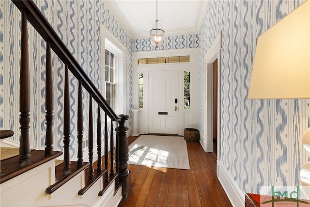 foyer entrance featuring ornamental molding, wallpapered walls, and hardwood / wood-style floors